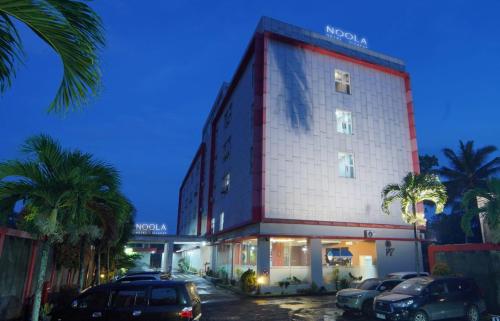 a building with cars parked in a parking lot at Noola Hotel Cilacap in Gumilir