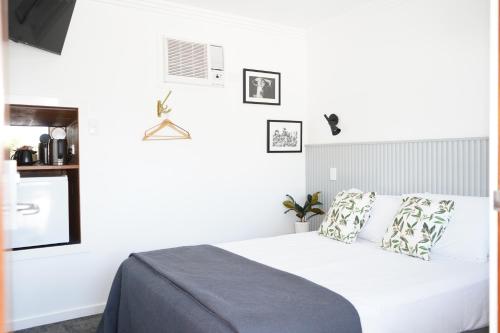 a bedroom with a bed with white sheets and pillows at Queensland Hotel in Goondiwindi
