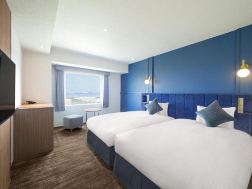 a hotel room with two beds and a blue wall at Oriental Hotel Tokyo Bay in Urayasu