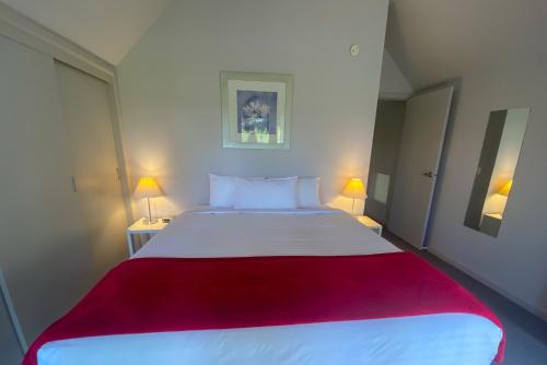 a bedroom with a large white bed with a red blanket at Edgewater Terraces at Metung in Metung