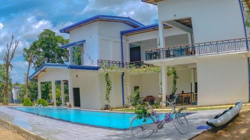 a house with two bikes parked in front of a swimming pool at Bungalow Resort - Sigiriya in Sigiriya
