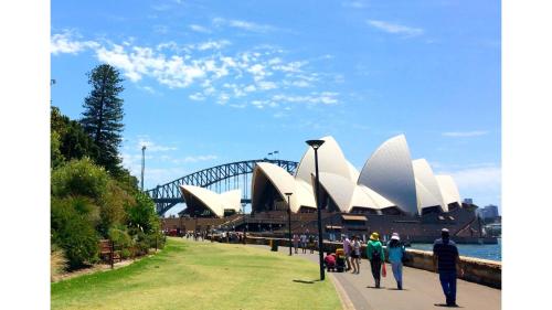 a group of people walking in front of the sydney opera house at Holiday Inn Sydney Potts Point in Sydney
