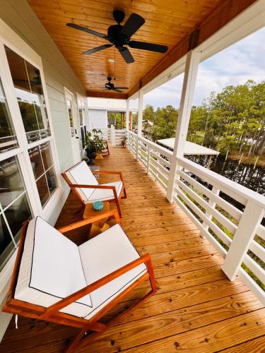 a porch with white chairs and a ceiling fan at Gulf Coast Waterfront Home in Shoreline Park