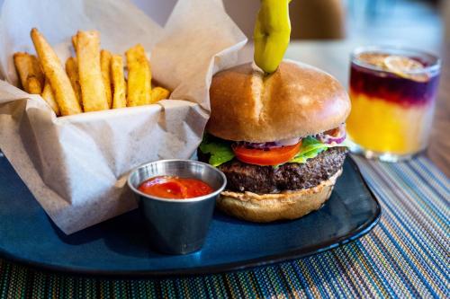 a hamburger and french fries on a plate with a drink at Hotel Indigo Austin Downtown - University by IHG in Austin