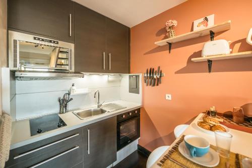 a kitchen with orange walls and gray cabinets at Ti Kaz Oreo - Cosy Plage & confort - Wiskeys in Saint-Gilles les Bains