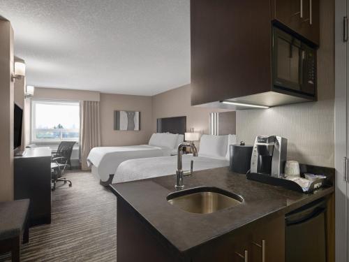 a hotel room with a bed and a sink at Holiday Inn Calgary Airport by IHG in Calgary