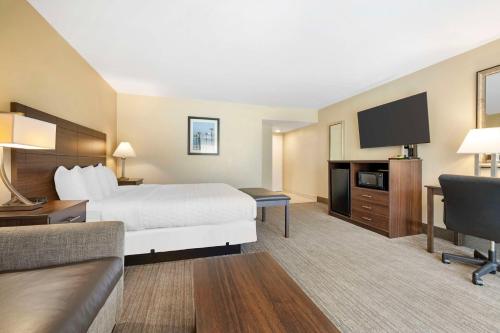a hotel room with a bed and a flat screen tv at Best Western Oceanside Inn in Oceanside