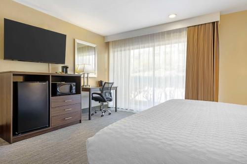 a hotel room with a bed and a flat screen tv at Best Western Oceanside Inn in Oceanside