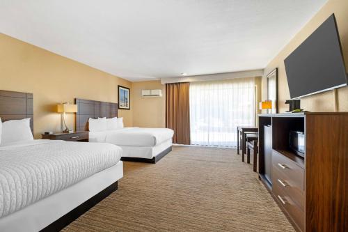 a hotel room with two beds and a flat screen tv at Best Western Oceanside Inn in Oceanside