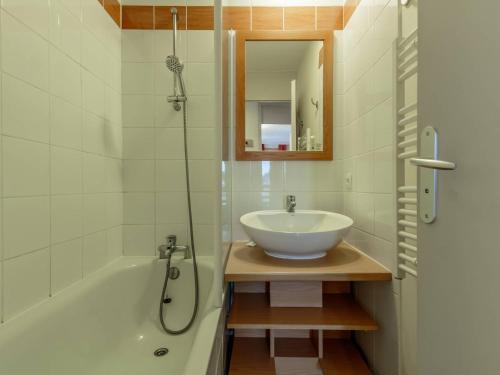 La salle de bains est pourvue d'un lavabo et d'une baignoire avec un miroir. dans l'établissement Appartement cosy à Plagne 1800 avec parking et piscine chauffée - FR-1-351-242, à La Plagne Tarentaise