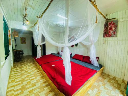 a bedroom with a red bed with a canopy at Chậm Homestay Đà Lạt in Da Lat