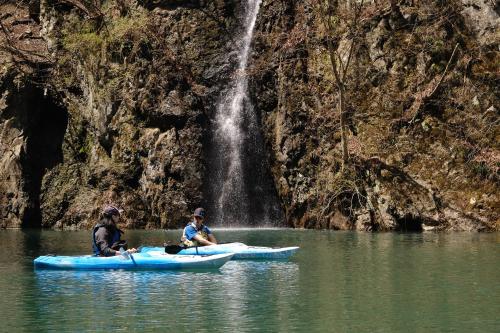 two people in kayaks in the water in front of a waterfall at Little Japan Echigo in Yuzawa