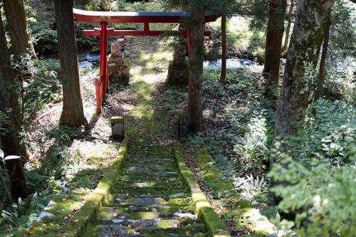 a stone path through a forest with a red gate at Little Japan Echigo in Yuzawa