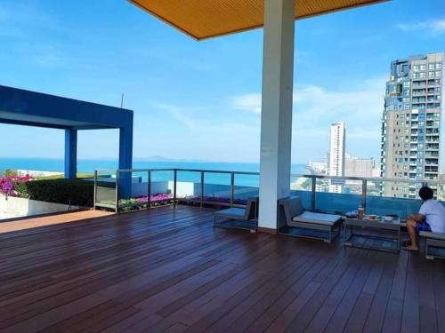 a person sitting on a balcony of a building at Studio Seaview Jomtien floor12 23sqm in Jomtien Beach
