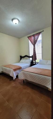 a bedroom with two beds and a window at Casa Bugambilias in Ajaxá