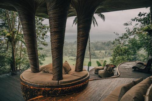 a cat laying on a swing on a wooden deck at Hideout Eco Bamboo House Bali in Selat