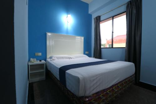 a blue bedroom with a large bed with a window at Hotel Sri Puchong in Puchong