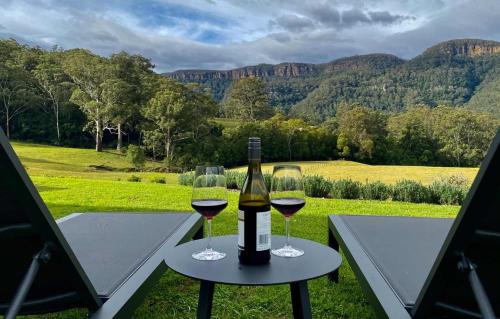 a bottle of wine and two glasses on a table at Amaroo Valley Springs in Barrengarry