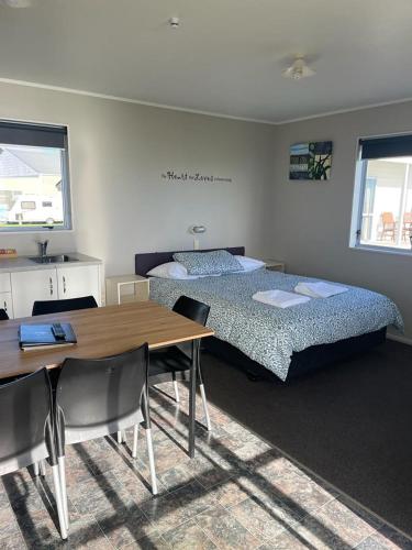 a bedroom with two beds and a table and a dining room at Belt Road Seaside Holiday Park in New Plymouth