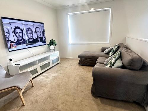 Una sala de estar con un sofá y un televisor de pantalla plana. en Coastal Oasis - 10 mins to Torquay, 10 mins to Geelong !, en Mount Duneed
