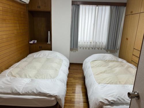 two beds in a small bedroom with a window at Marina Bay Atami in Atami