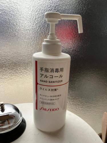 a bottle of hand sanitizer on a table next to a clock at ゲストハウスわたうさぎ in Tsuruoka