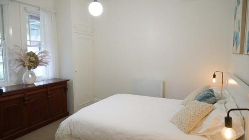 a white bedroom with a bed and a window at Stay on March in Orange