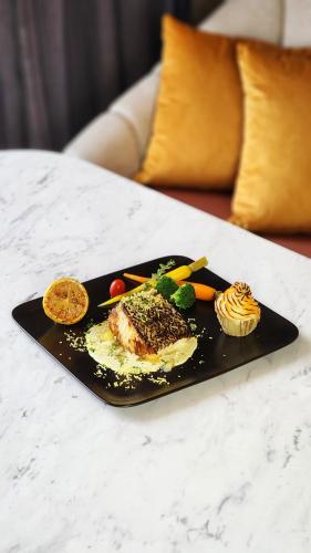 a black plate with food on a table at Imperial Lexis Kuala Lumpur in Kuala Lumpur