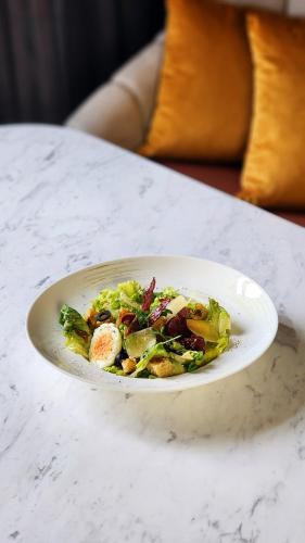 a white plate with a salad on a table at Imperial Lexis Kuala Lumpur in Kuala Lumpur
