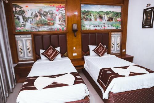 two beds in a room with paintings on the wall at Vientiane Garden Villa Hotel And Coffee in Vientiane