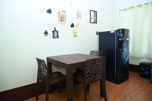 a table and chairs and a refrigerator in a room at Axom Aura in Tezpur