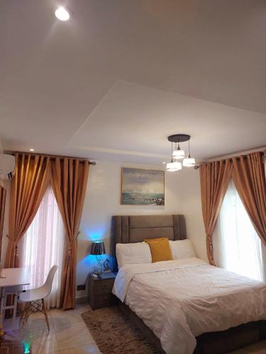 a bedroom with a bed and a desk and two windows at Professionals Friendly with Work Station PS5 & near Beaches in Lekki