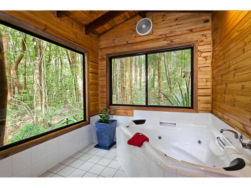 baño con bañera y ventana en The Mouses House Rainforest Retreat, en Springbrook