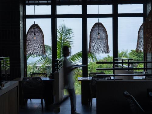 a person walking through a restaurant with windows at Glamday Style Okinawa Yomitan Hotel & Resort in Yomitan