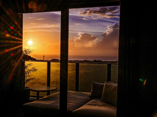 a view of a sunset from a room with a couch at Glamday Style Okinawa Yomitan Hotel & Resort in Yomitan