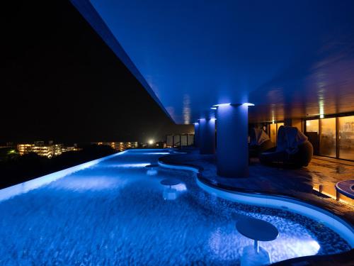 a swimming pool on top of a building at night at Glamday Style Okinawa Yomitan Hotel & Resort in Yomitan