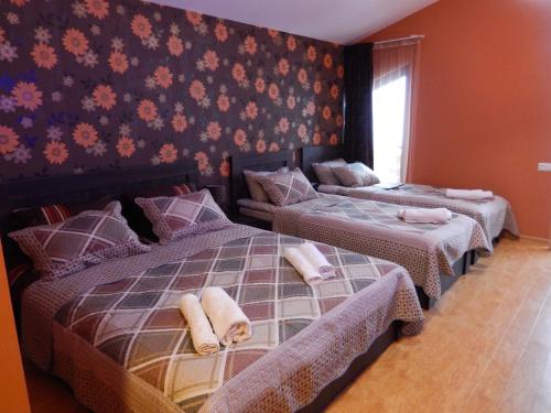 a bedroom with two beds and a wall with flowers at Cottage Sunny Side in Bakuriani