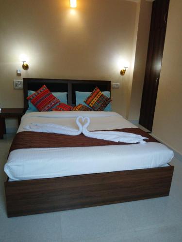 a bedroom with a large bed with white sheets at Joel's River Wood in Pernem