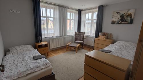 sypialnia z 2 łóżkami, krzesłem i oknami w obiekcie Apartman692 w Vrchlabi