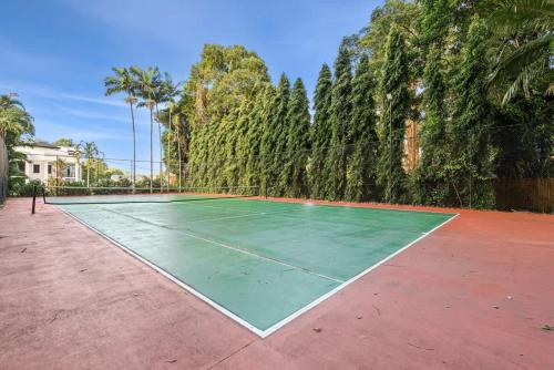an empty tennis court with trees in the background at The MAGNA by Reef Stays in Palm Cove