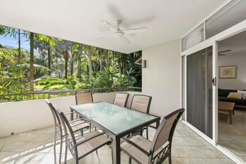 a dining room with a glass table and chairs at THE GRANDÈ by Reef Stays in Palm Cove
