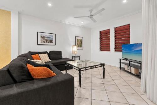 a living room with a couch and a flat screen tv at The MAGNA by Reef Stays in Palm Cove