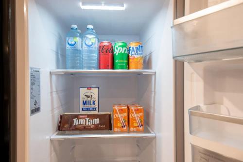 a refrigerator filled with drinks and a box of milk at THE GRANDÈ by Reef Stays in Palm Cove