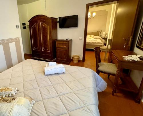 a bedroom with a large bed and a desk and a room with a bedicter at Hotel Rifugio la Foresta in Vallombrosa
