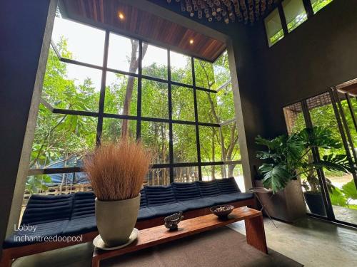 a room with a large window with a bench and plants at Inchantreedoopool in Kanchanaburi