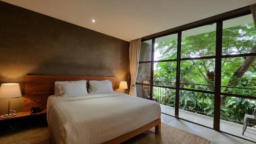 a bedroom with a bed and a large window at Inchantreedoopool in Kanchanaburi City