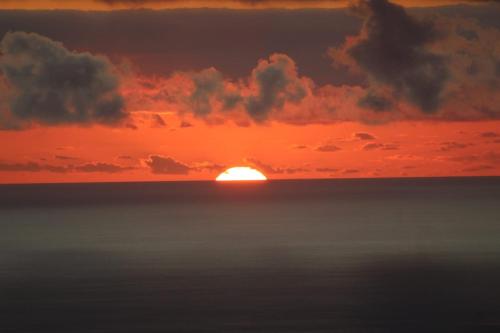 a sunset over the ocean with the sun in the horizon at Chez Pack et Ibu in Petite Île