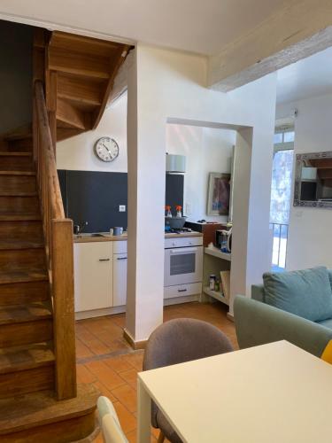 Una cocina y una sala de estar con un reloj en la pared. en Le bel angle, en Arles