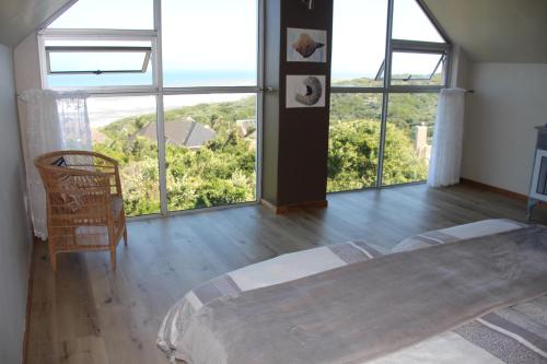 a bedroom with large windows and a bed and a table at Ungabona in East London