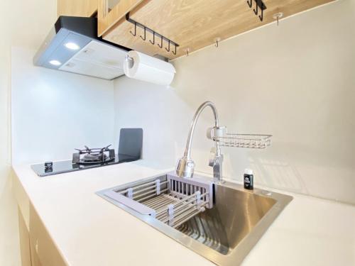 Una cocina con un fregadero en una encimera blanca. en Comfort Designed 1BR Apartment at Gateway Pasteur By Travelio, en Bandung